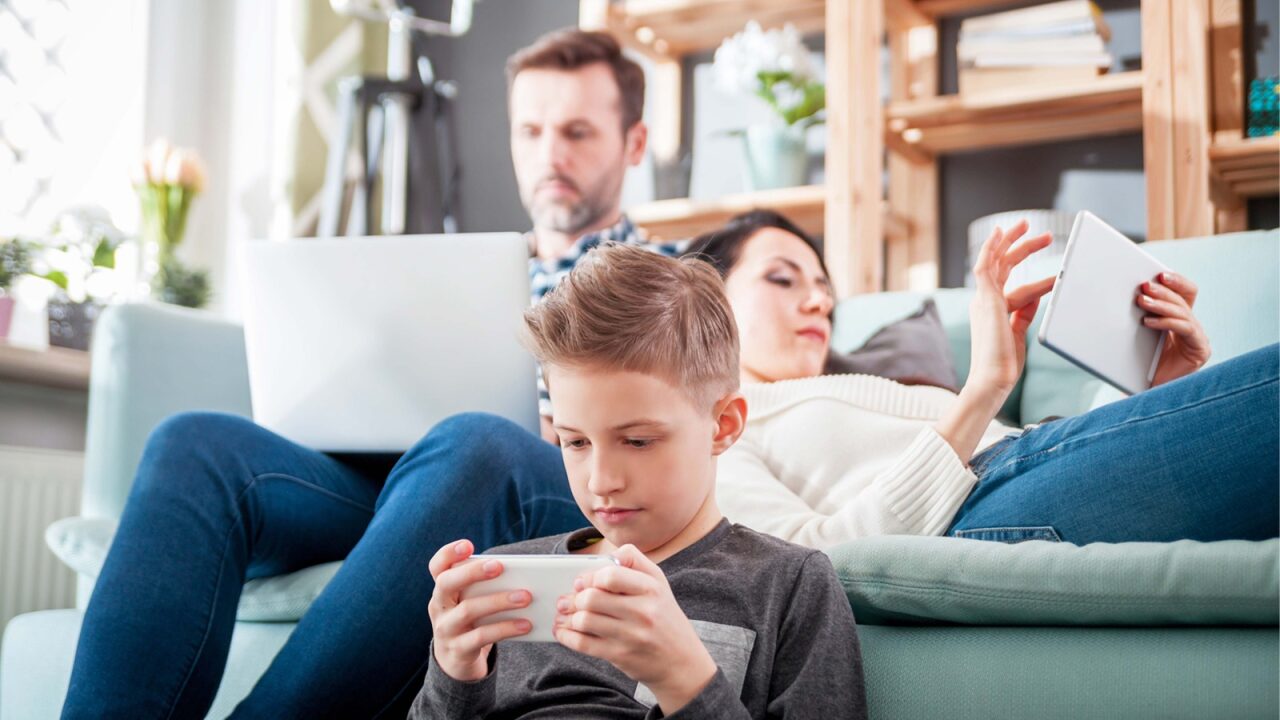 Family sitting in their living room using multiple devices.